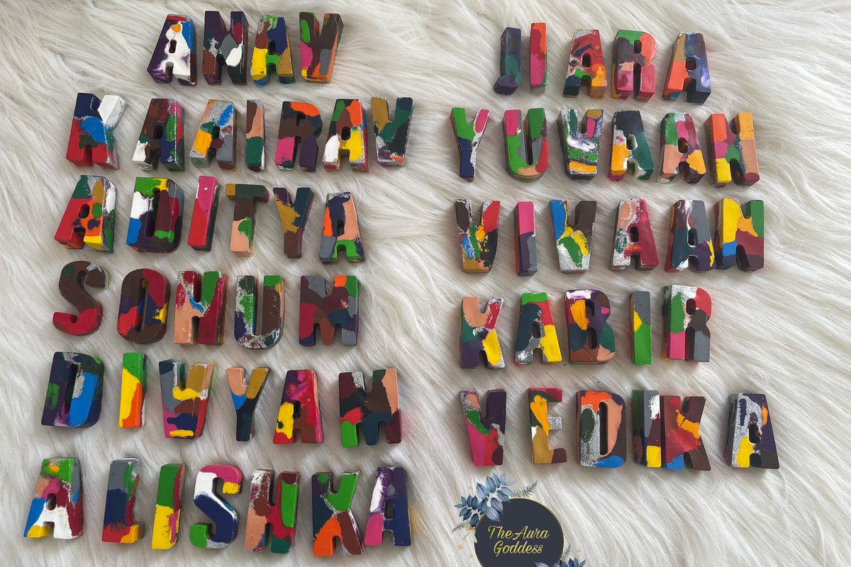 Multicolor painted crayon name letters arranged on a white faux fur background, with a small circular logo at the bottom right.