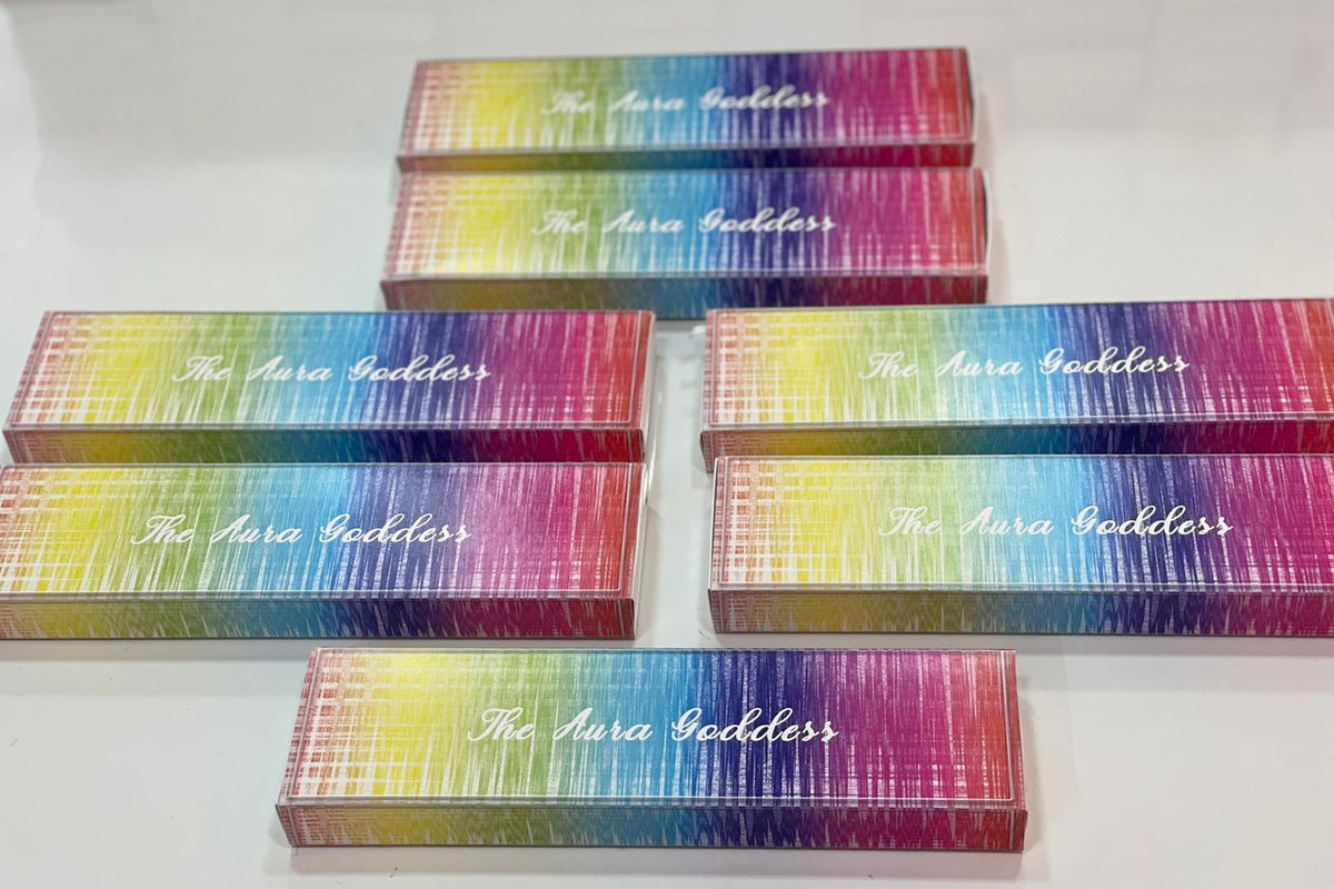 Six rectangular boxes with a colorful rainbow gradient and white cursive text reading 'The Aura Goddess' arranged on a plain white surface.