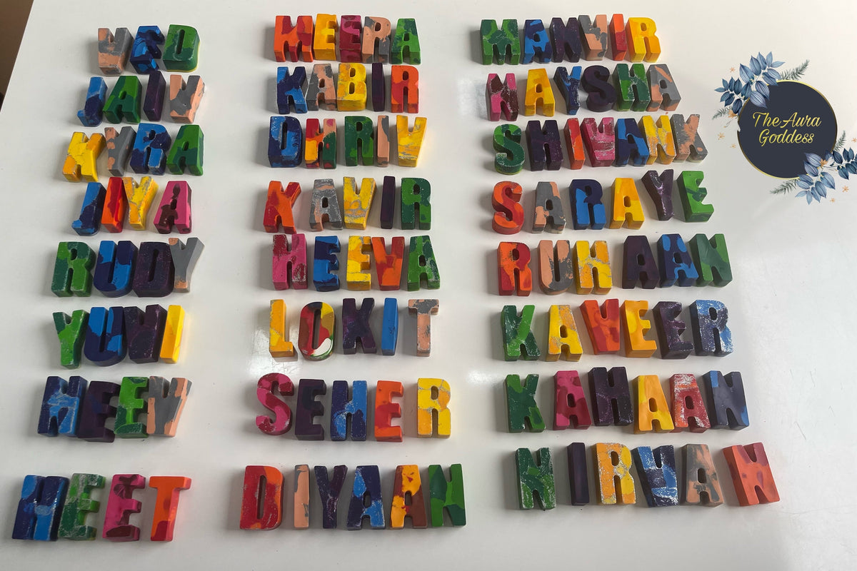 Personalized handmade rainbow name crayons with colorful letters spelling kids names like Meera, Manvir, Naysha arranged on white background by The Aura Goddess