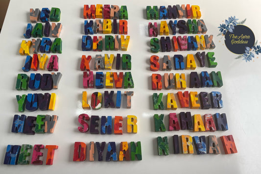 Personalized handmade rainbow name crayons with colorful letters spelling kids names like Meera, Manvir, Naysha arranged on white background by The Aura Goddess